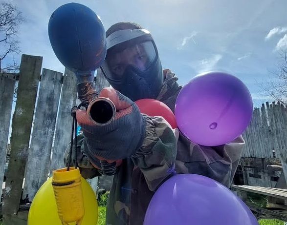 Joueur en tenue de paintball avec des ballons pour un anniversaire